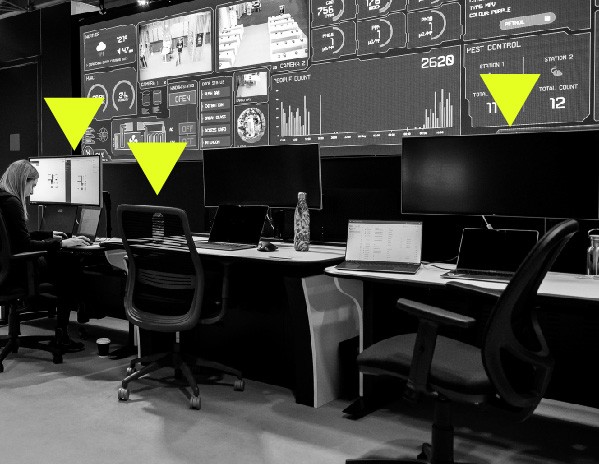 Black and white image of office space with screens. Yellow arrows pointing out facilities.